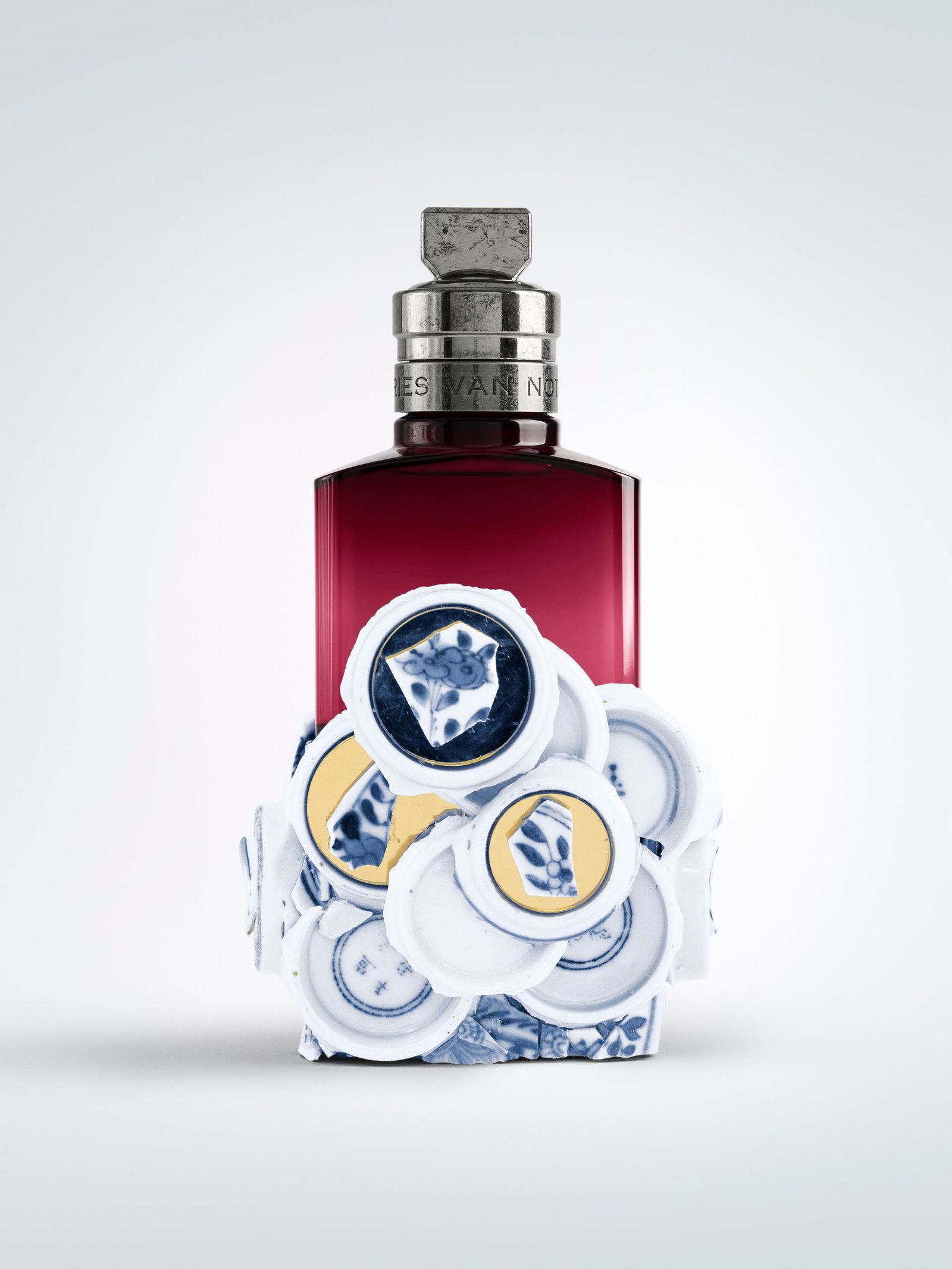 Perfume bottle with button decorative elements on a light grey background - Dries Van Noten