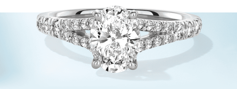 Oval cut diamond engagement ring set in white gold with pavé diamonds along a split band.