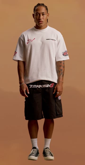 an image of a man standing in a white shirt and black shorts