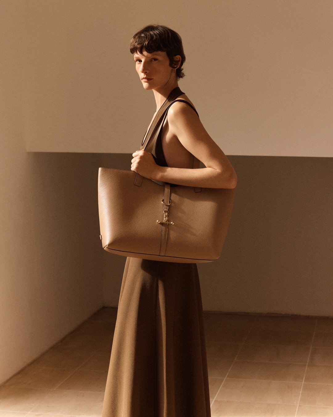 an image of a woman in a long dress carrying a large bag