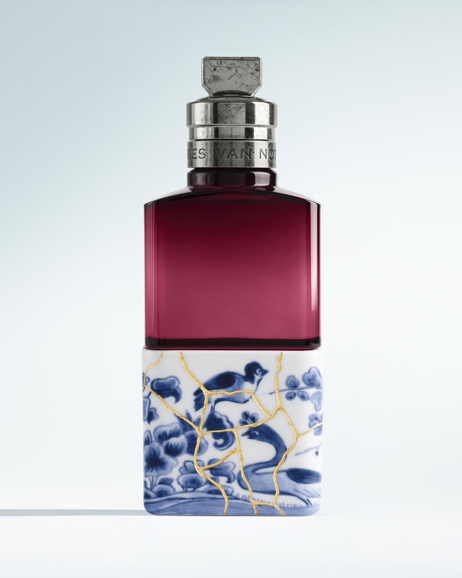 Soie Malaquais golden perfume bottle with blue and white patterned box on a light gray background - Dries Van Noten