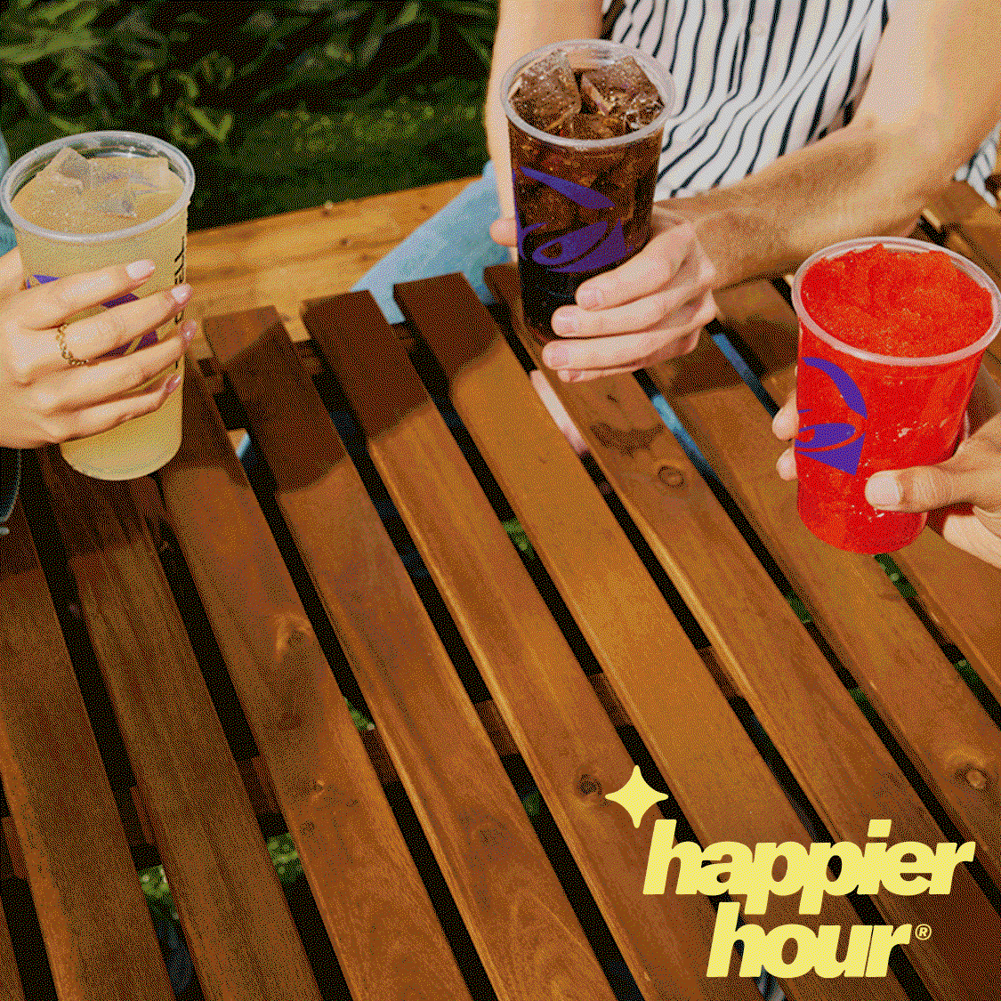 Happier hour: three friends sitting around a table clinking various Fountain Drinks and Freezes together.
