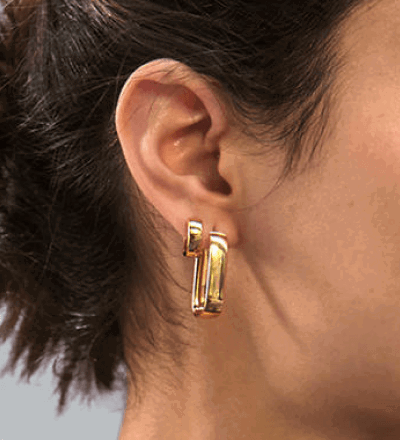 Model Wearing Chunky Yellow Gold Huggie Hoop Earrings, Small and Elongated Styles.