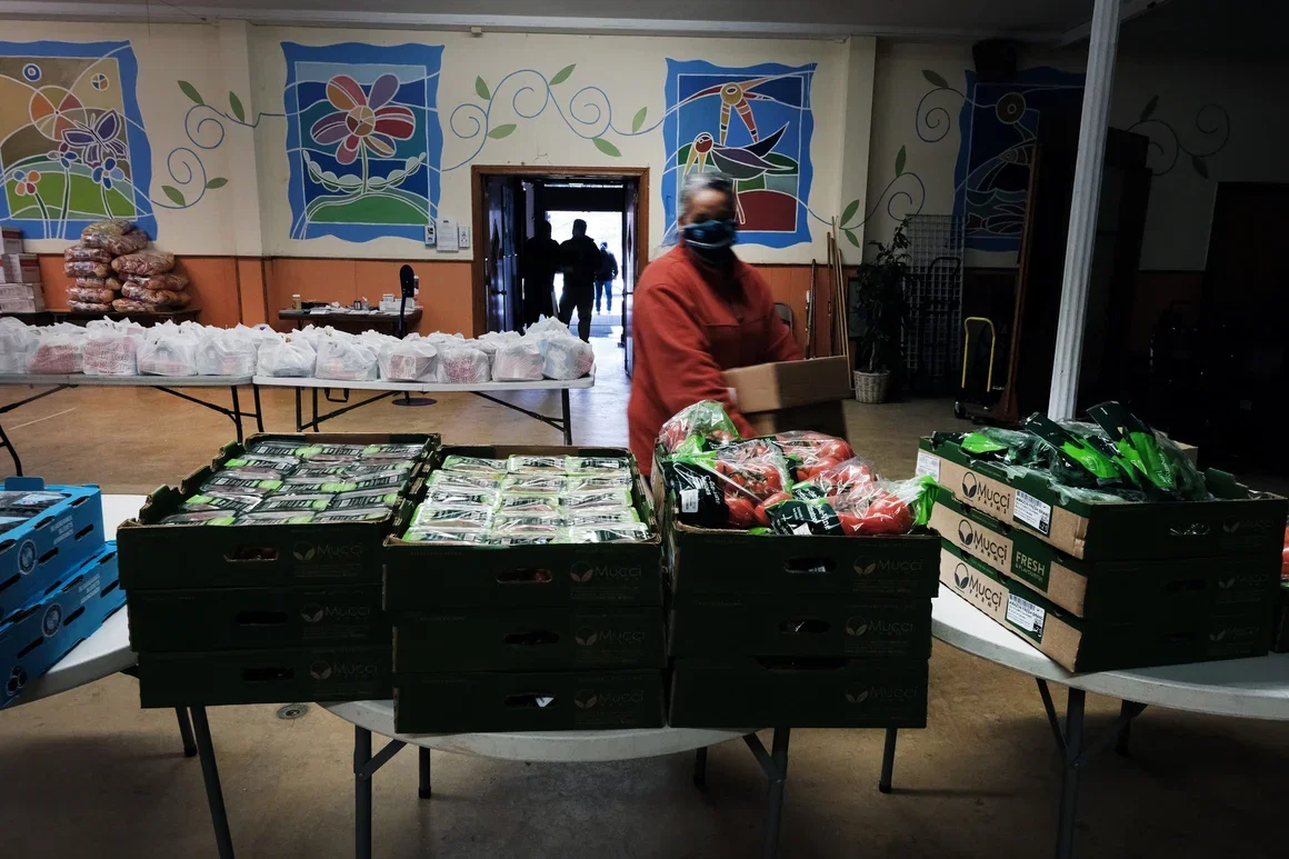 Volunteers stocking a food pantry with boxes of fresh produce and packaged goods in Kensington.