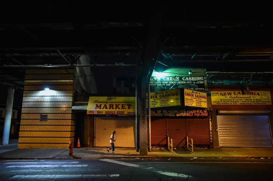 Kensington Avenue at night with check cashing shops and shuttered storefronts lit by fluorescent signs.