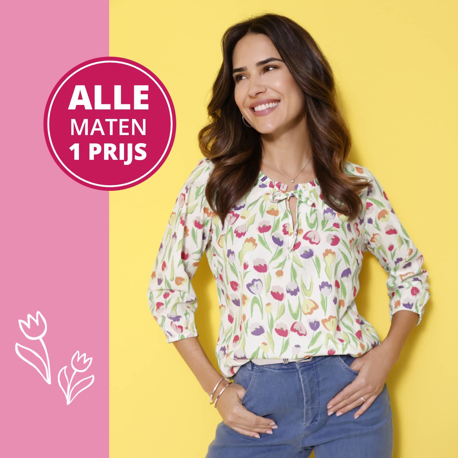 Een model draagt een blouse met kleurrijk tulp-patroon en een blauwe spijkerbroek voor een gele achtergrond. Alle maten één prijs.