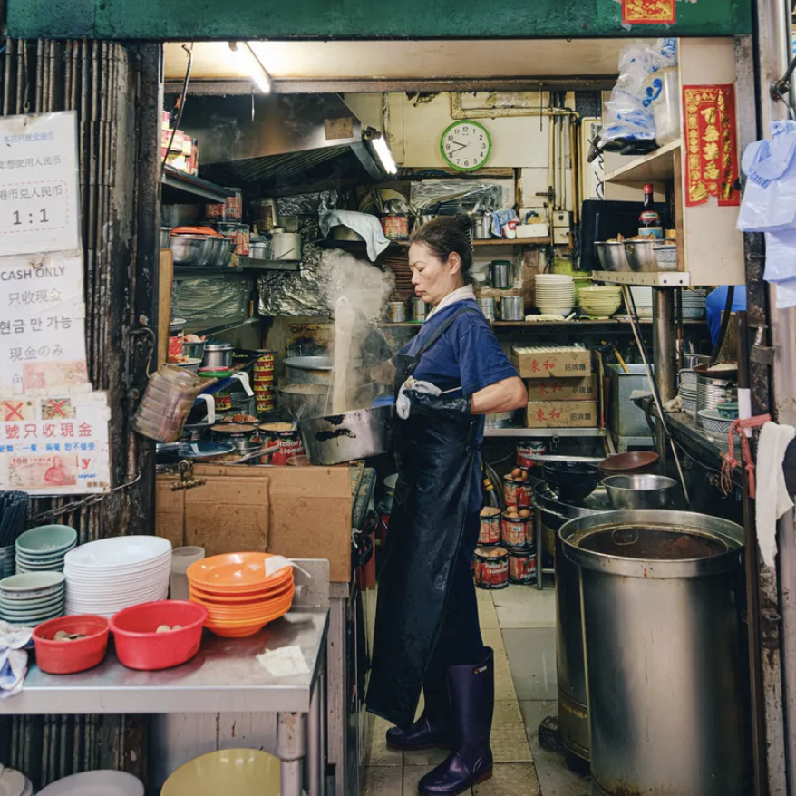 A woman cooking in the kitchen outside in from a food stall