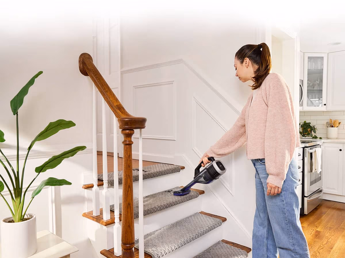 Woman cleaning indoor home stairs using the dustbuster® reveal™ Cordless Handheld Vacuum