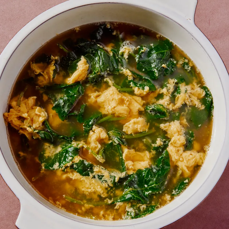 Bone Broth Egg drop soup in a white bowl on beige surface