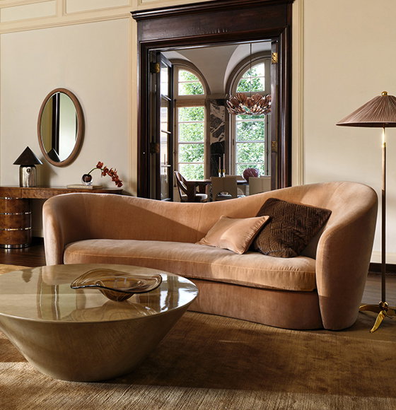 A warm toned living room with a couch, coffee table and lamps.