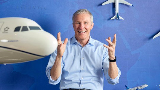 Scott Kirby smiles in front among models of United Airlines planes