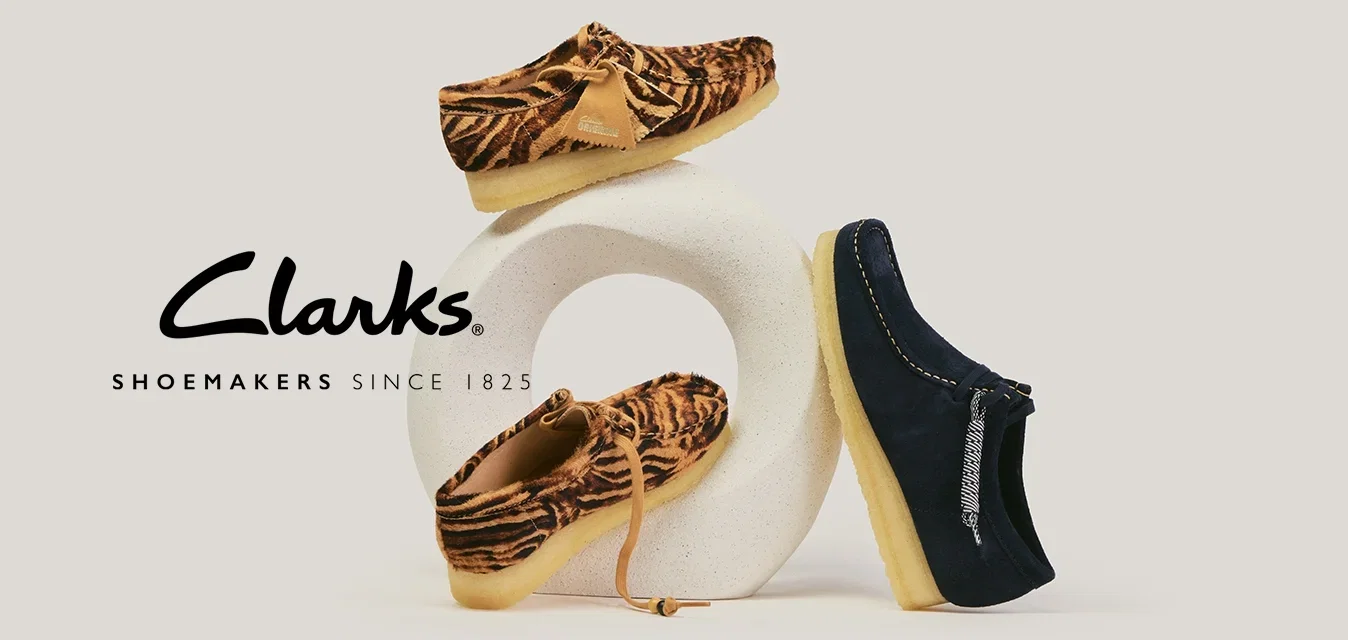 Deux mocassins à imprimé tigre marron et un mocassin bleu marine avec une semelle beige, présentés sur un support sculptural blanc.