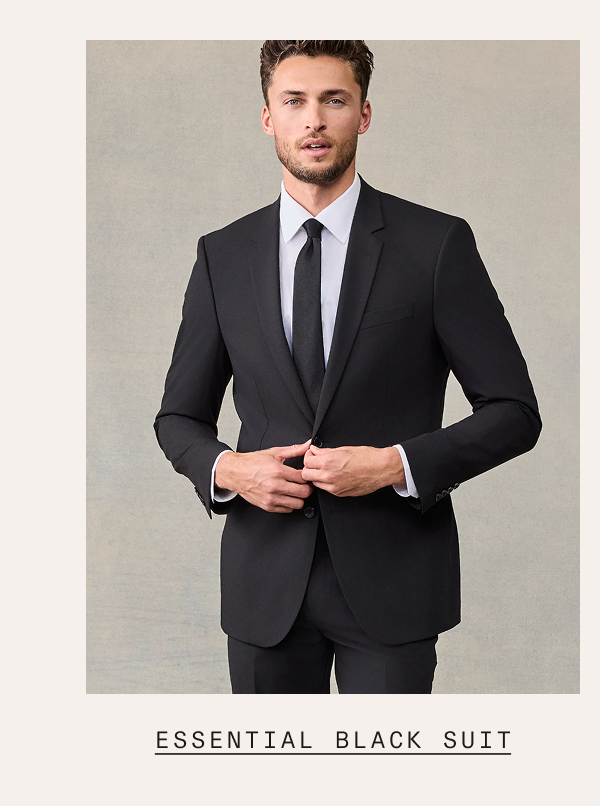A man wearing an essential black suit with a light blue dress shirt and black tie, buttoning his jacket and looking at the camera. Text below reads: "ESSENTIAL BLACK SUIT"