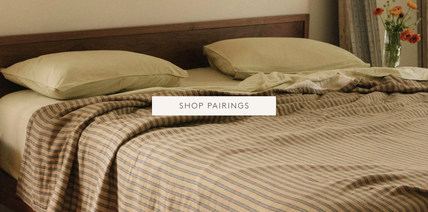 Striped coverlet and yellow sheets on a wooden bed frame
