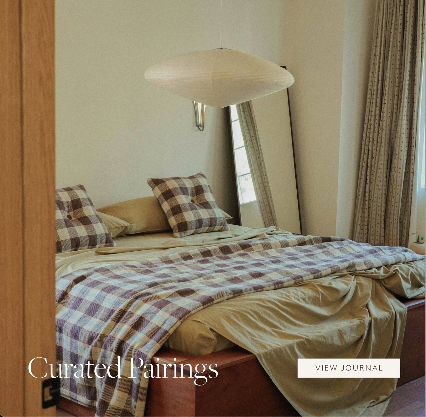 Brown check blanket and square pillows with light green sheets on a bed.