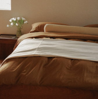 Blue green duvet on a bed with a checkered rug and side table