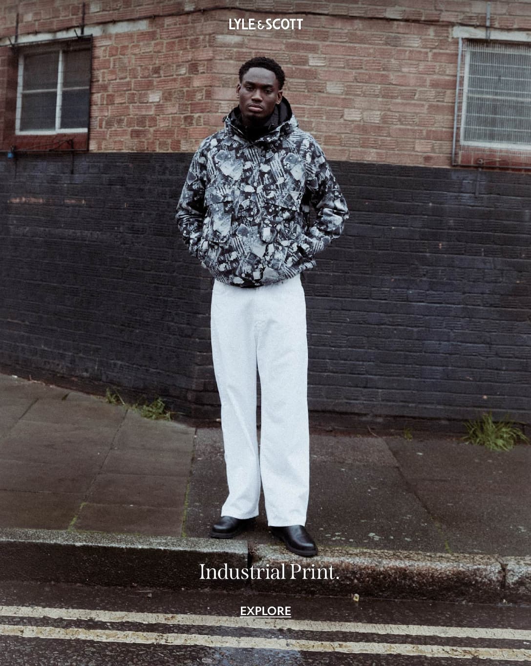 Model wearing Industrial Print Hooded Anorak Jacket, paired with white jeans and leather boots