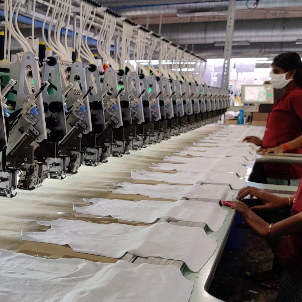The inside of a fabric factory, showing garment workers working on t-shirts.