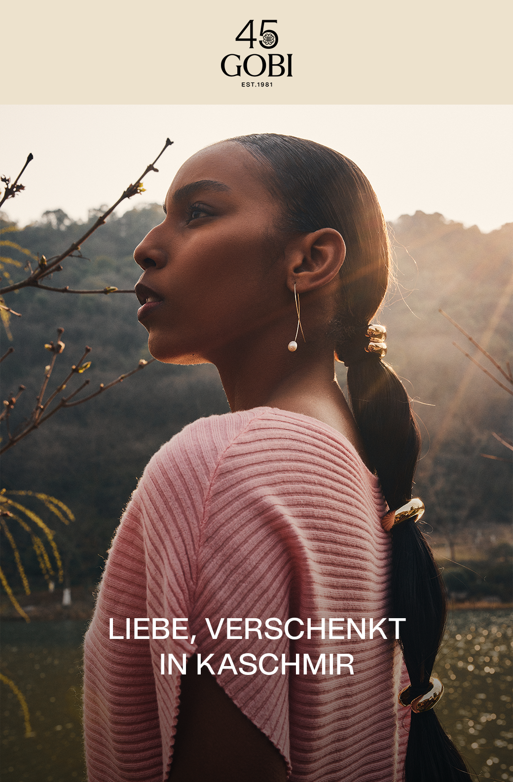 Eine Frau in einem rosafarbenen Kaschmir-Top im Freien, mit dem Text „Love Given in Cashmere“ .