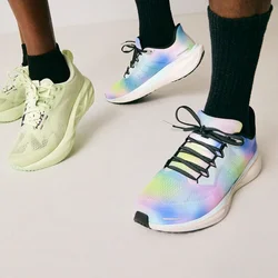 Deux personnes portant des chaussettes noires et des chaussures de sport colorées, se tenant sur un sol de couleur claire devant un fond uni.
