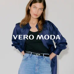 Jeune femme portant une chemise en satin bleu foncé sur un débardeur noir, un jean taille haute bleu clair et des talons pointus noirs à œillets.