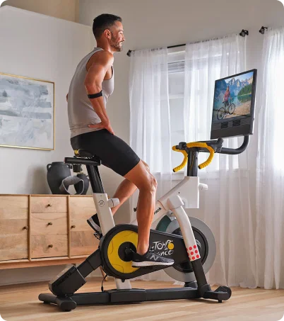 Man riding NordicTrack Tour de France bike with large console display at home