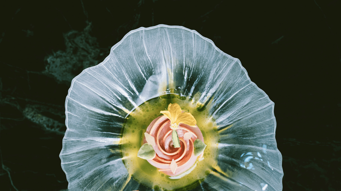 Artfully plated fine-dining dish presented on a sculptural glass plate.