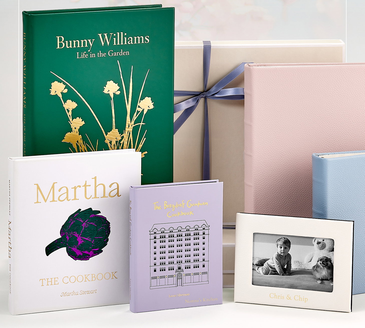 Leather-bound editions of Bunny Williams: Life in the Garden, Martha: The Cookbook By Martha Stewart, and The Bergdorf Goodman Cookbook, along with leather photo albums and picture frames.