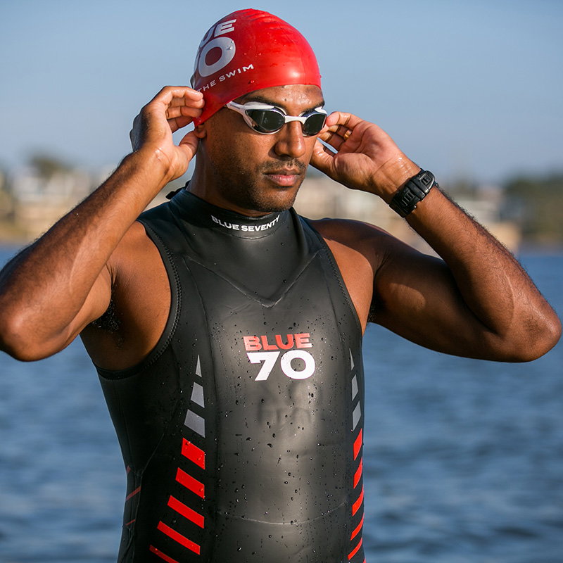 Swimmer in Reaction Sleeveless adjusts a red swim cap.