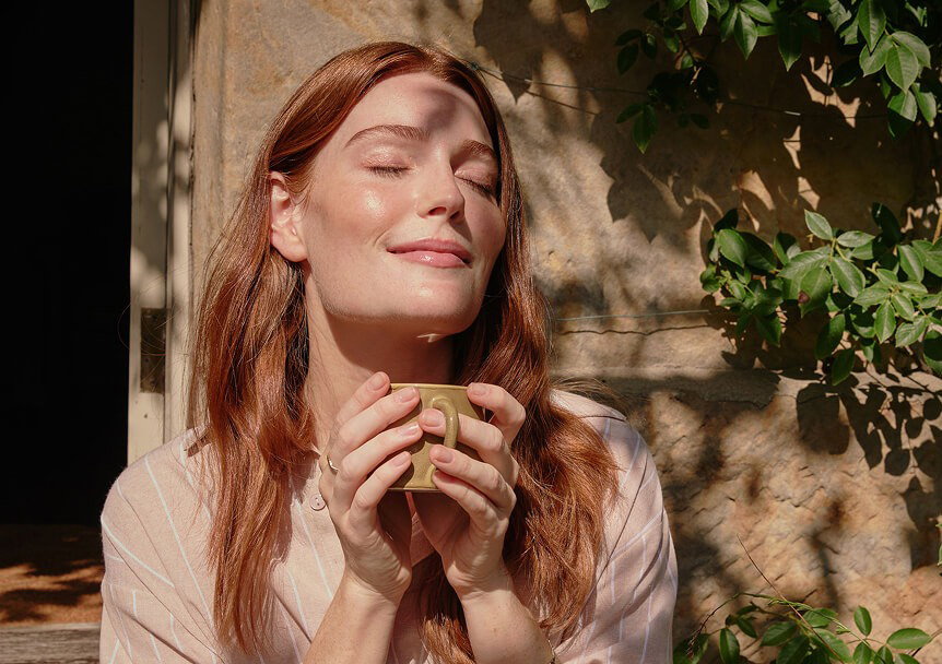 Woman basking in the sun with a mug