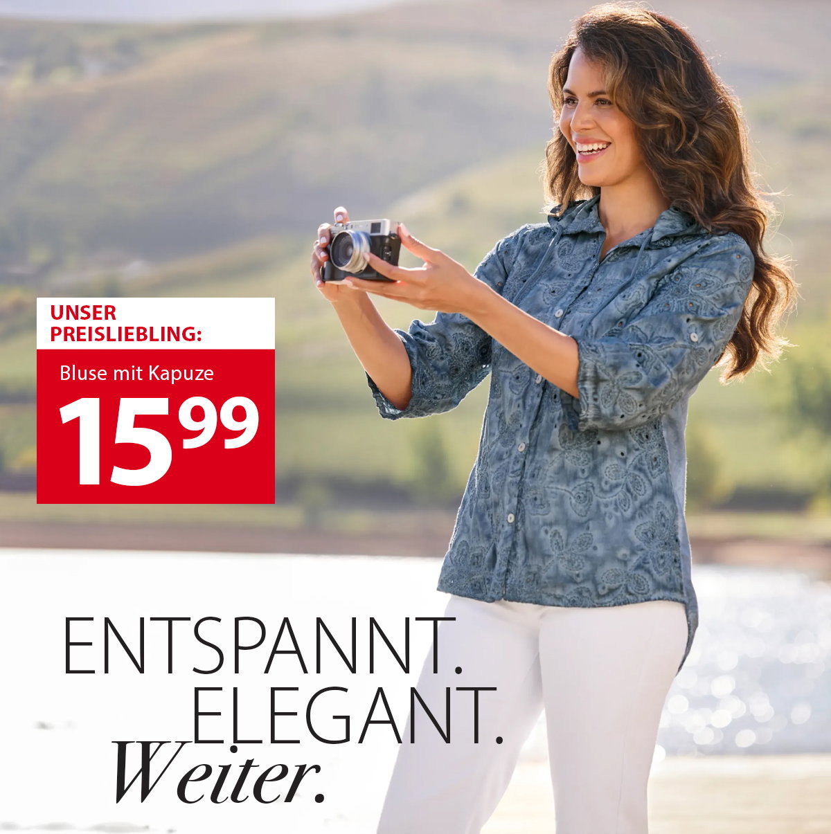 Frauenmodel trägt blaue, bemusterte Bluse mit Kapuze, weiße Hose, seitliche Pose, Kamera in der Hand, Text: entspannt, elegant, weiter, Natur im Hintergrund.