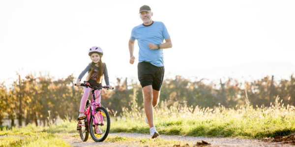 Joggender Mann neben Mädchen auf Fahrrad