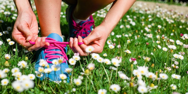 Person, die in Frühlingswiese Laufschuhe schnürt