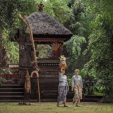 Guests walk through a serene temple garden with carved stone pavilion.