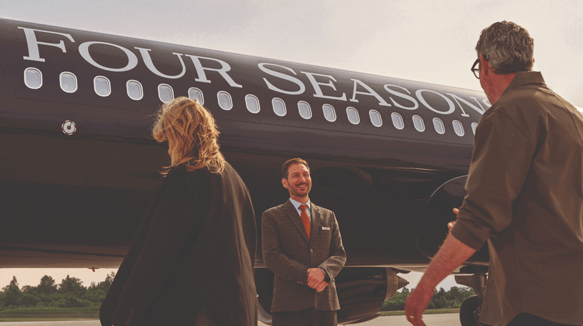 Guests welcomed beside a Four Seasons private jet on the tarmac.