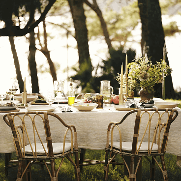 Elegant dining table arranged beneath trees.