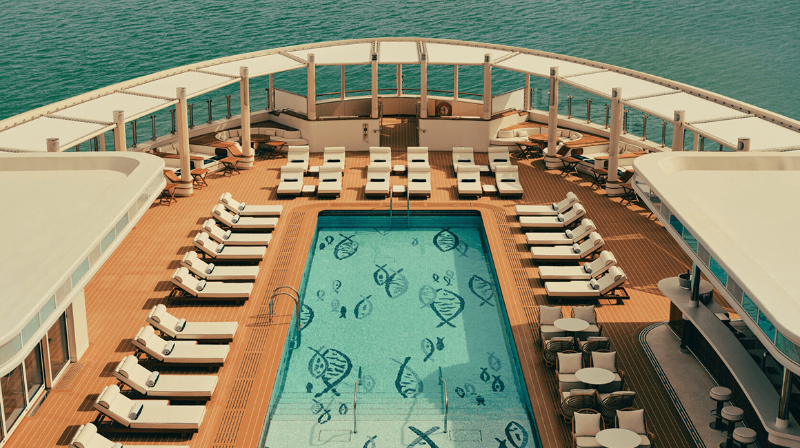 Pool deck with loungers and ocean views aboard a luxury yacht.