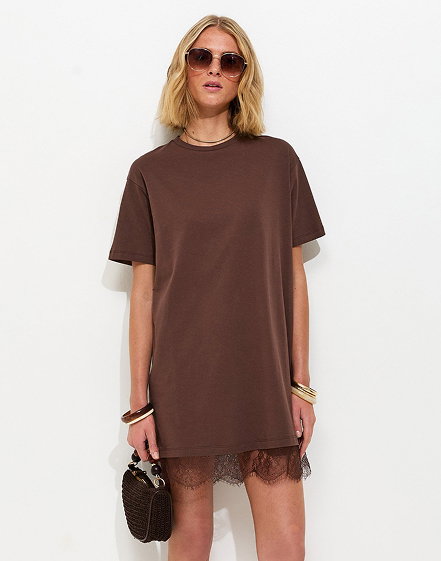 Model wearing a brown polka dot midi dress with ruffle straps, styled with brown sandals, gold jewellery, and a small handbag.