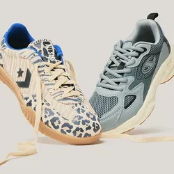 Twee sneakers met veters los, zwevend naast elkaar; één blauwgrijze mesh en één beige met dierenprint en een gumzool.