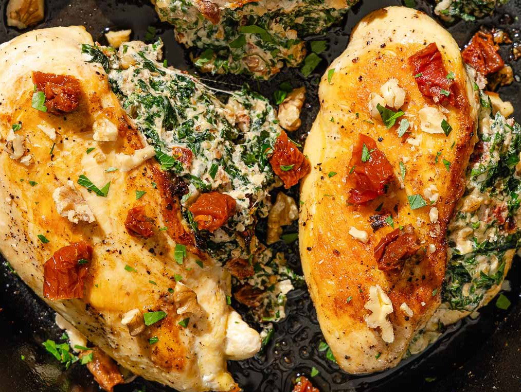 Two stuffed chicken breasts in a cast iron skillet.