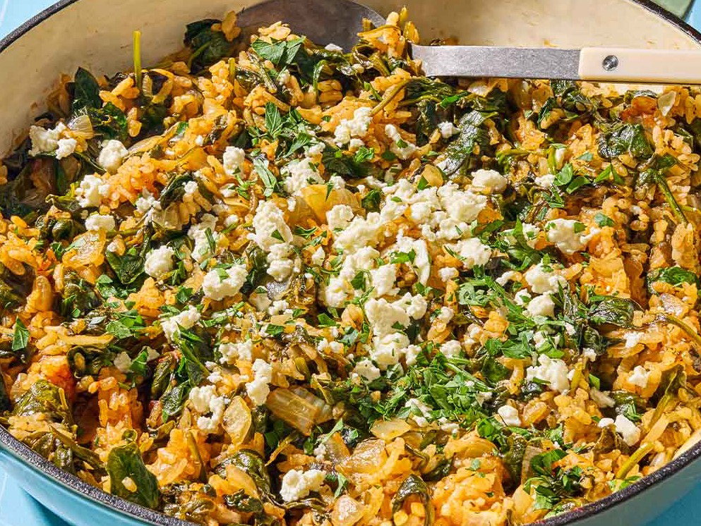 Spanakorizo Greek spinach rice in a skillet with a serving spoon.