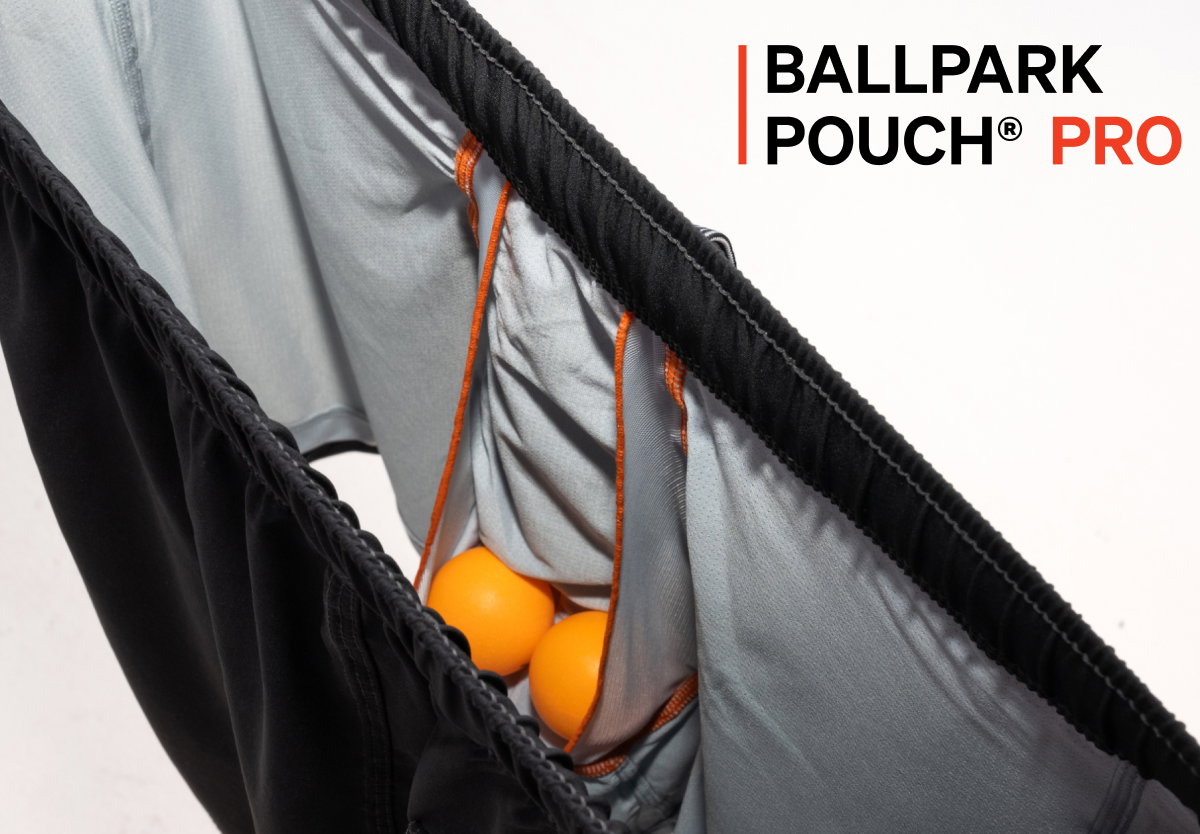 Close-up of athletic shorts showing the BallPark Pouch Pro liner with orange support panels holding small balls inside.