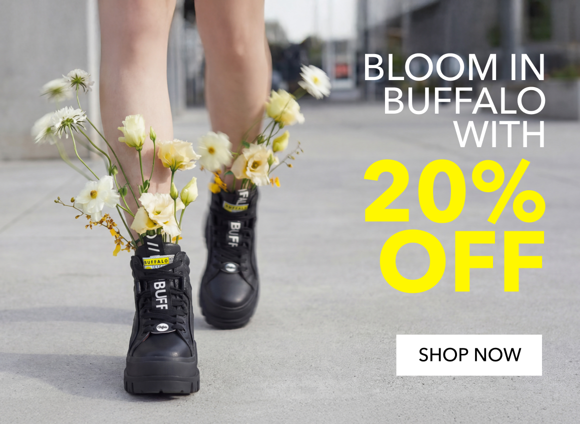 A person walks on a city sidewalk wearing black platform boots, with small white and yellow flowers tucked into the laces. On the right side, text reads “Bloom in Buffalo with 20% off,” with “20% off” highlighted in bright yellow.