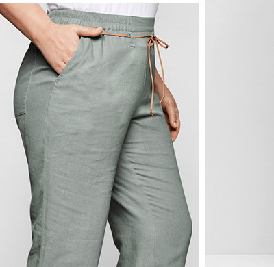 Model in salbengrüner Leinenhose mit braunem Bindeband
