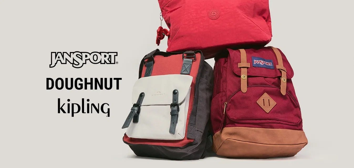 Tres mochilas en tonos rojos y beige dispuestas contra un fondo liso gris claro.