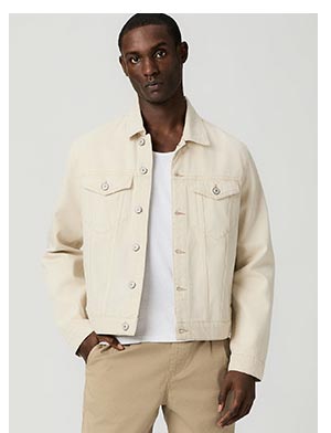 A man wearing a light cream colored denim jacket with white ribbed tank and khaki pants.