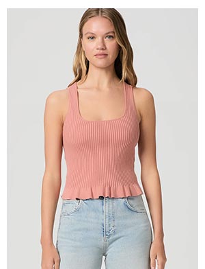 A woman wearing a pink rib tank and light wash blue denim jeans.