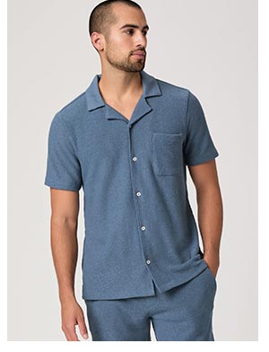 A man wearing a blue short sleeve button up shirt paired with matching shorts.