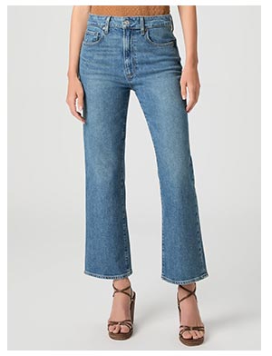 A woman's legs wearing medium blue wash denim jeans and dark brown leather strappy sandals.