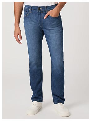 A man's legs wearing a darker medium vintage wash blue jean and white shoes.